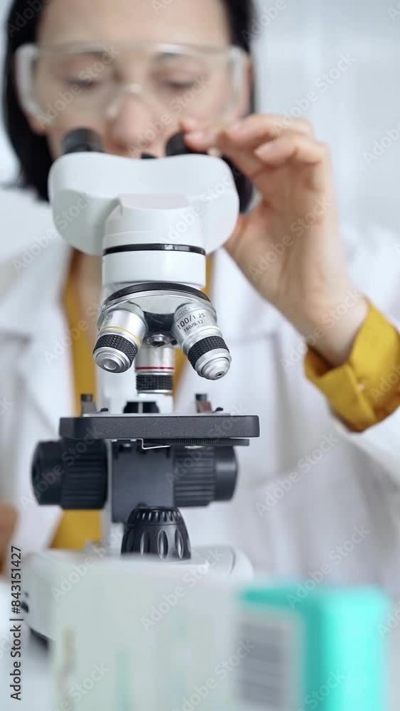 Woman scientist with protective glasses using microscope in laboratory. Microbiology science concept Woman scientist with protective glasses using microscope in laboratory. Microbiology science concept