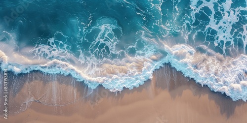 Aerial view of ocean waves crashing on sandy shore