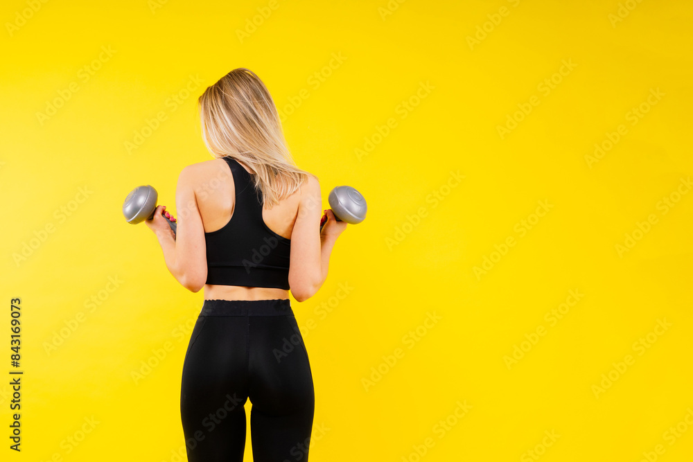 Strong woman working out with dumbbells, flexing her arm. Photo of sporty female in sportswear. Strong woman working out with dumbbells, flexing her arm. Photo of sporty female in sportswear.