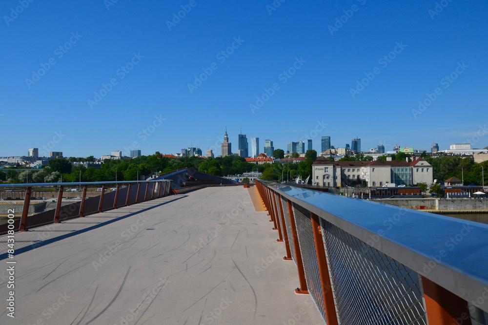 Obraz premium New brigde in Warsaw, Poland. Pedestrian and bicycle footbridge over the Vistula River. Warsaw skyline