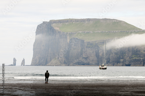 Tjornuvik beach on Streymoy island, Faroe Islands, Denmark. Lonely yacht and tourist on faroese beach. Landscape photography photo