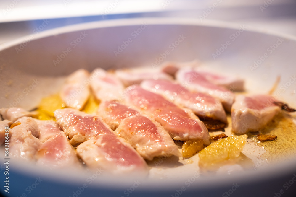 a fresh and natural turkey breast cut into fillets is cooked in a white granite pan with a little organic extra virgin olive oil and onion slices a fresh and natural turkey breast cut into fillets is cooked in a white granite pan with a little organic extra virgin olive oil and onion slices