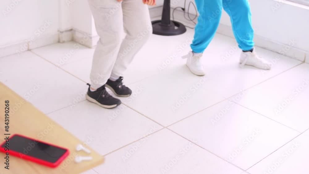 Legs view of women dancing in white dance salon in blur, phone and earphones on table Legs view of women dancing in white dance salon in blur, phone and earphones on table