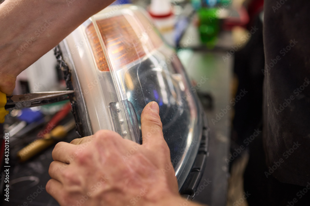 showing hands effectively repairing a car headlight in a workshop environment showing hands effectively repairing a car headlight in a workshop environment