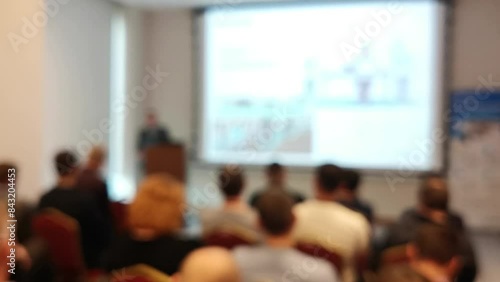 Blurred defocused footage with back view of audience in a business conference or seminar. Audience listens to the lecturer at the conference in auditorium.