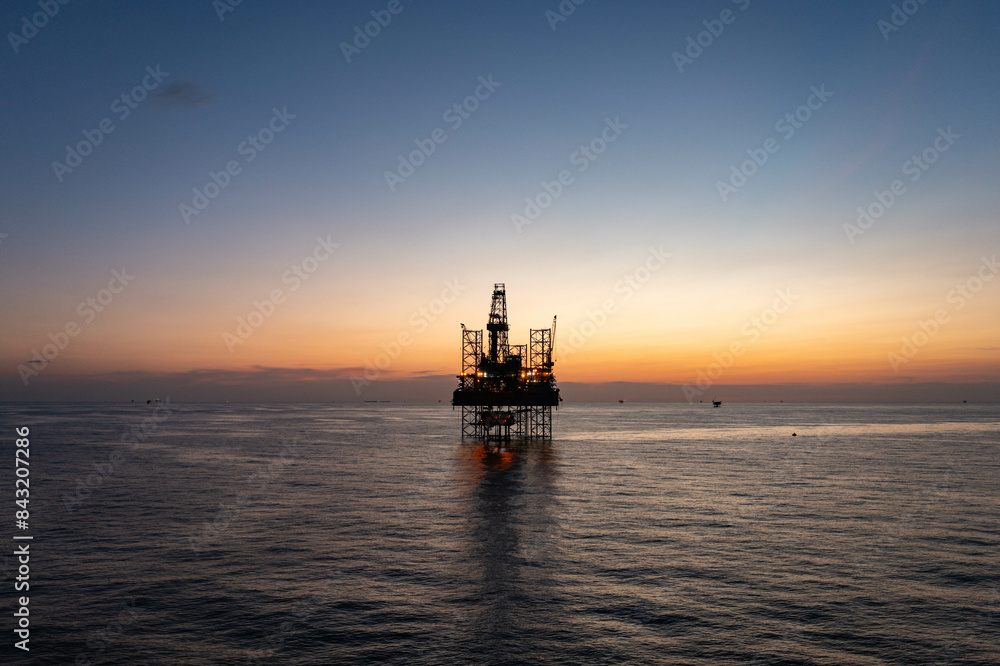 Aerial view of silhouette offshore jack up drilling rig during sunset - oil and gas industry. Aerial view of silhouette offshore jack up drilling rig during sunset - oil and gas industry.