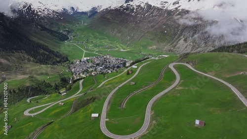 The alpine village of Andermatt surrounded by green meadows, and snowy peaks in the background, Canton of Uri, Switzerland, Europe