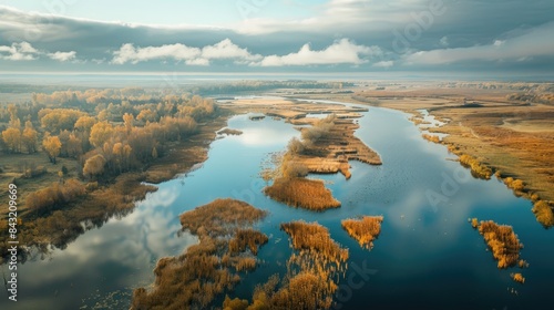 Autumn aerial view of river valley with reeds on riverbanks under a cloudy sky