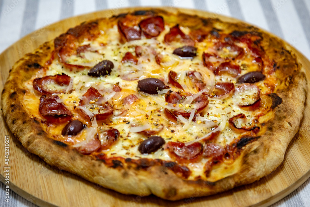 Calabrian sausage pizza served on a round board and set table Calabrian sausage pizza served on a round board and set table