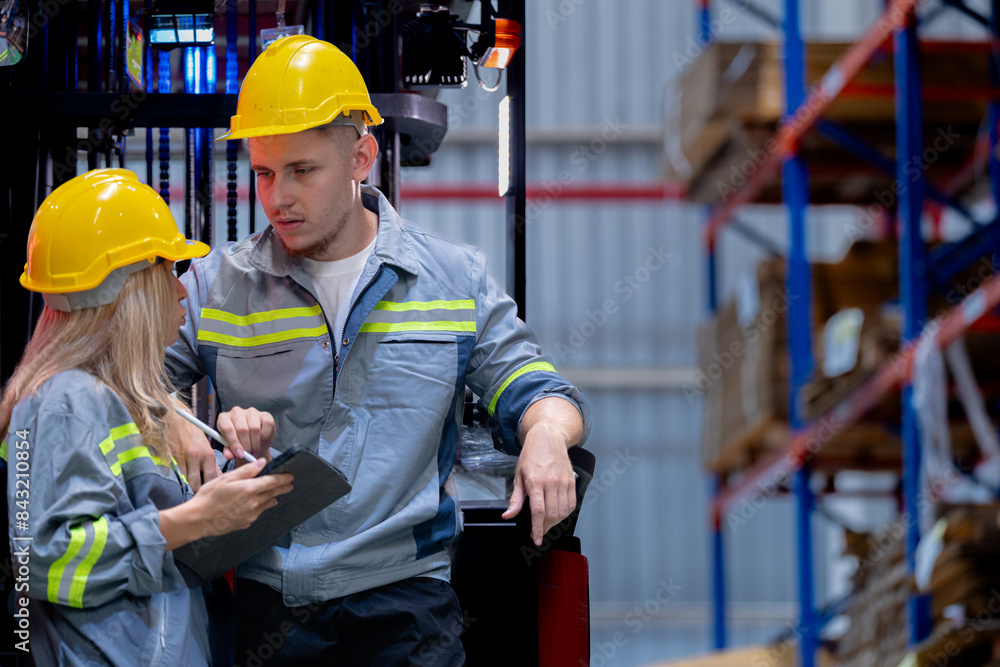 Two male and female factory checkers are discussing work on a warehouse truck. While working in a warehouse for industrial products Two male and female factory checkers are discussing work on a warehouse truck. While working in a warehouse for industrial products