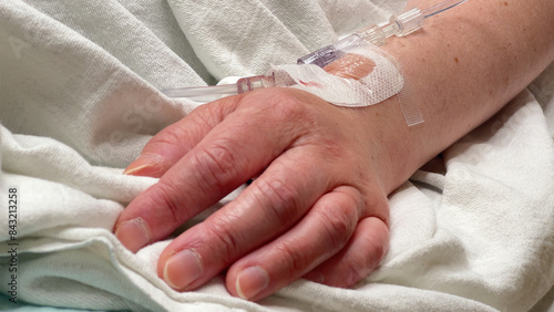 Patient laying in hospital bed with IV in wrist