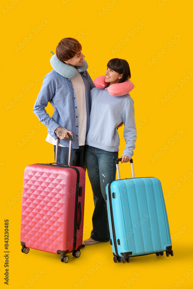 Couple of young tourists with suitcases on yellow background Couple of young tourists with suitcases on yellow background