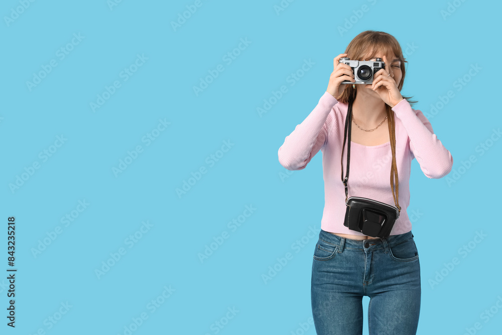 Beautiful young woman with camera and bag on blue background