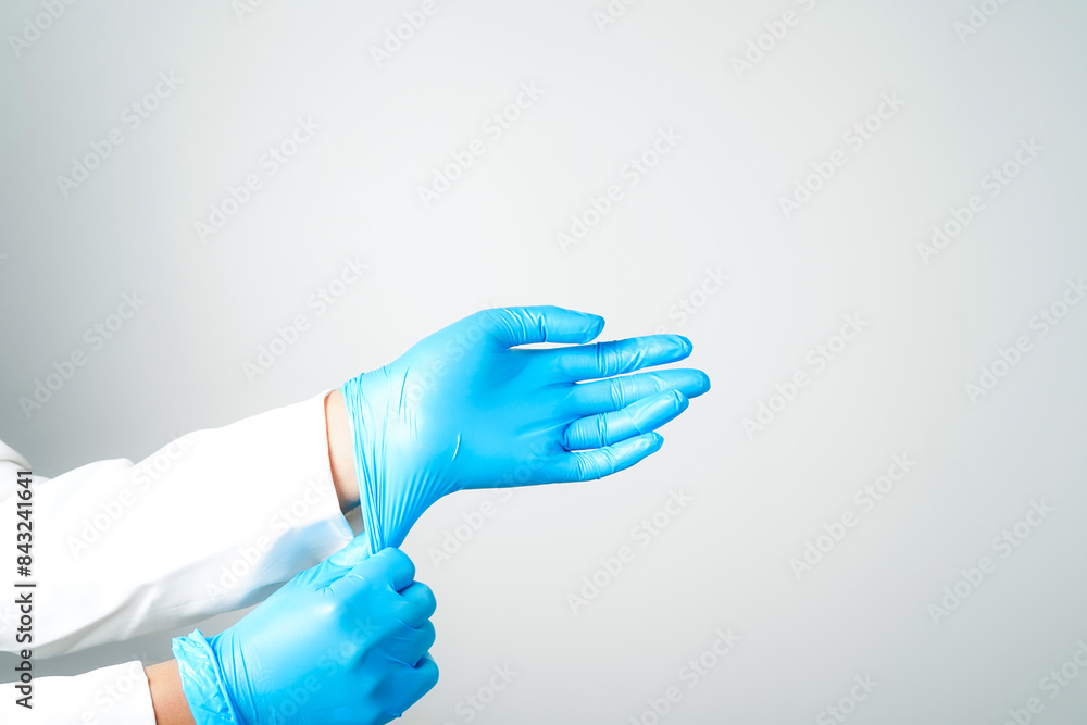 Two hands of a man wearing nitrile blue gloves on a white background Two hands of a man wearing nitrile blue gloves on a white background