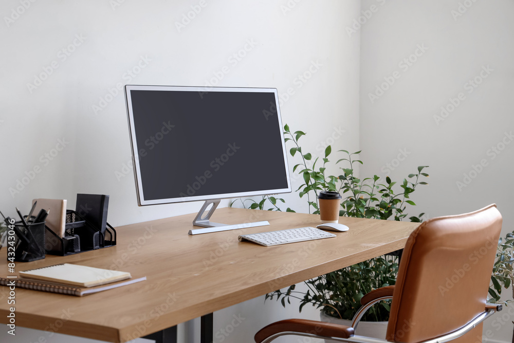 Modern workplace with computer monitor, coffee cup and houseplant in office Modern workplace with computer monitor, coffee cup and houseplant in office