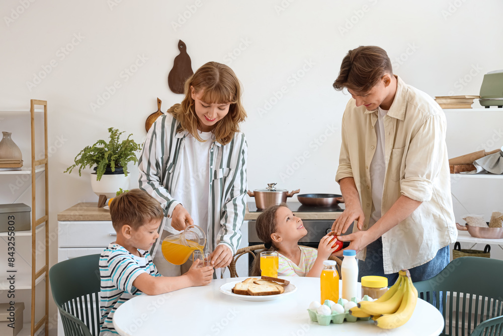 Little children with their parents having breakfast at table in kitchen Little children with their parents having breakfast at table in kitchen