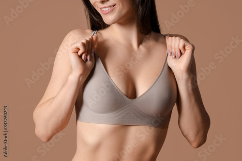 Young woman in seamless bra on brown background, closeup
