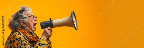 Elderly woman shouting into a megaphone against an orange background expressing opinion communication activism loud announcement senior citizen vibrant expressive concept

