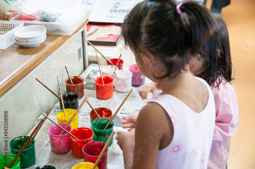 絵画教室でカラフルな絵の具で絵を描く小学生の子ども