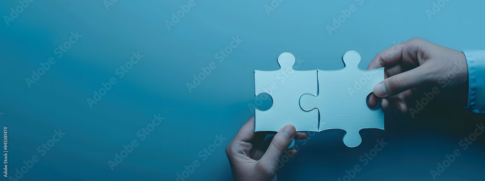 Two hands of business people connecting puzzle pieces on a blue background with copy space, symbolizing collaboration and teamwork. Background for business solutions, success, and strategy. Two hands of business people connecting puzzle pieces on a blue background with copy space, symbolizing collaboration and teamwork. Background for business solutions, success, and strategy.