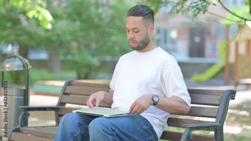 Young Man Leaving Bench after Closing Laptop Young Man Leaving Bench after Closing Laptop