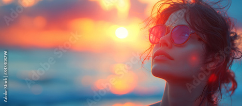 Woman wearing sunglasses against sunset on a beach. Summer vacation concept. Design for tourism advertising and lifestyle magazine. Banner with copy space.