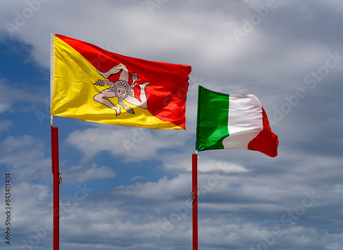 Italian and Sicilian flags flutter by wind and blue sky in San Vito lo Capo, Sicily, Europe 