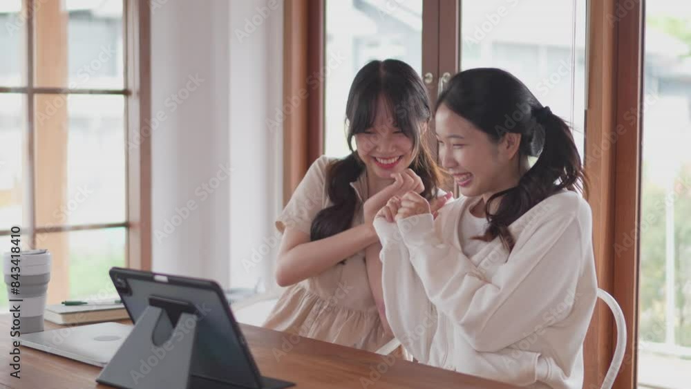 Two Asian female friends are watching a romantic movie on a tablet at home Two Asian female friends are watching a romantic movie on a tablet at home