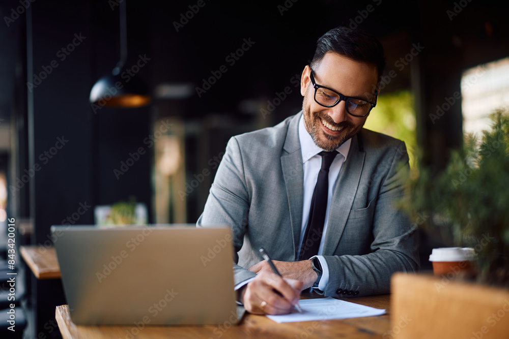 Happy entrepreneur working on business reports while using laptop in cafe, Happy entrepreneur working on business reports while using laptop in cafe,