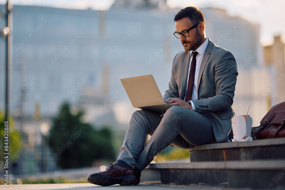 Mid adult businessman working on laptop in city. Mid adult businessman working on laptop in city.