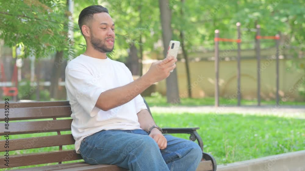 Outdoor Sitting Middle Aged Man Doing Video Chat on Smartphone Outdoor Sitting Middle Aged Man Doing Video Chat on Smartphone