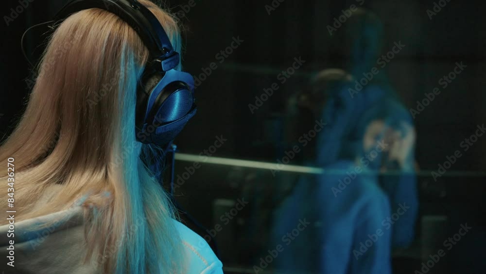 Professional female singer and sound engineer recording musical album in studio . Woman and man communicating through glass, creative and technical group of record label talented musicians working Professional female singer and sound engineer recording musical album in studio . Woman and man communicating through glass, creative and technical group of record label talented musicians working