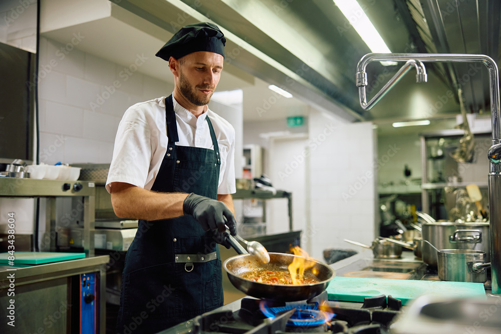 Male chef cooking while working in kitchen. Male chef cooking while working in kitchen.