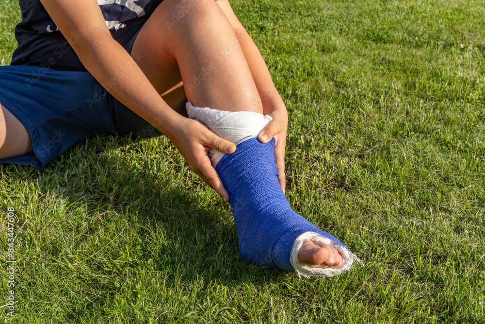 Leg in plaster boy with a broken leg in a cast during a football match an injury to a young athlete
Leg in plaster boy with a broken leg in a cast during a football match an injury to a young athlete