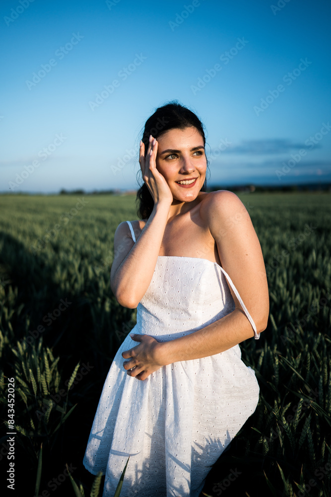 Beautiful woman in a white dress posing and dancing in a green wheat field. Freedom concept.Photo session in a green wheat field Beautiful woman in a white dress posing and dancing in a green wheat field. Freedom concept.Photo session in a green wheat field