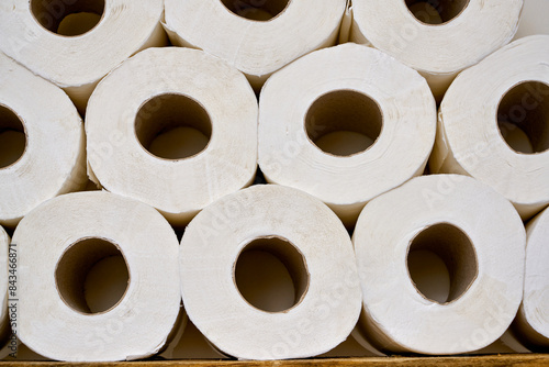 Pile of white toilet papers on a shelf in a white bathroom.