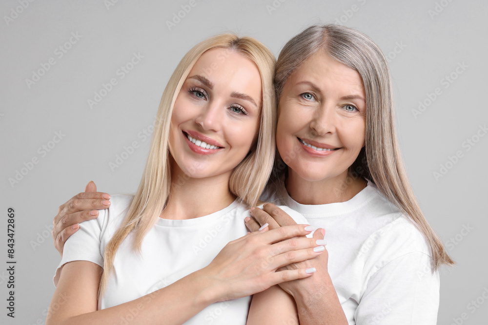 Family portrait of young woman and her mother on light grey background Family portrait of young woman and her mother on light grey background