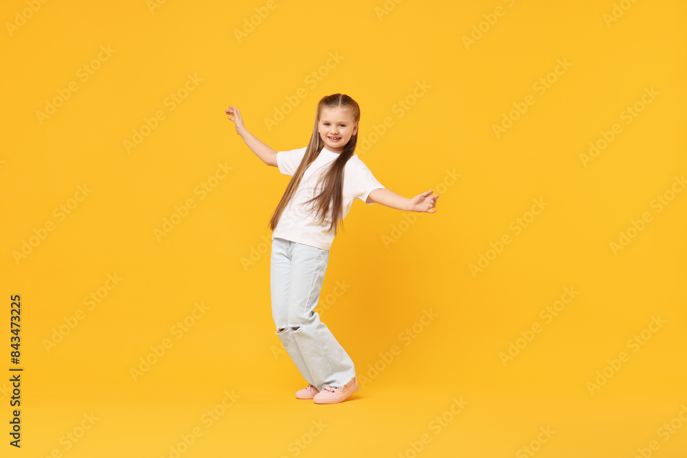 Cute little girl dancing on yellow background, space for text