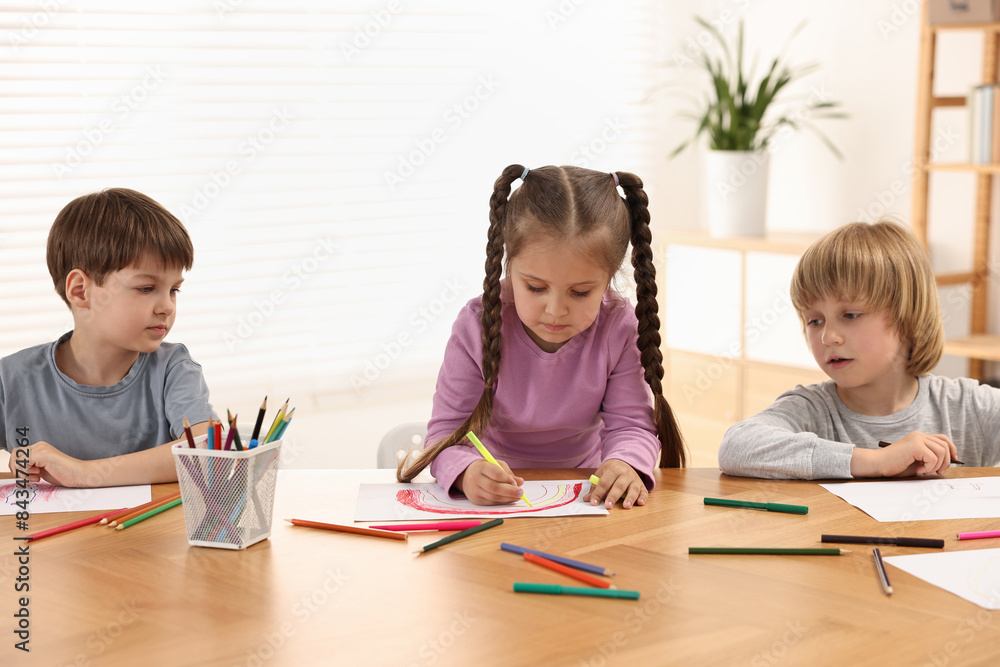 Cute little children drawing at wooden table indoors Cute little children drawing at wooden table indoors