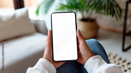Mockup woman's hand holding using smart phone with white blank screen POV  at coffee shop, mobile app design and advertising, online marketing