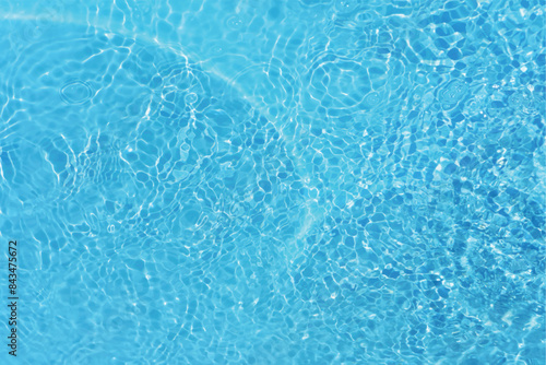 Blue water with ripples on the surface. Defocus blurred transparent blue colored clear calm water surface texture with splashes and bubbles. Water waves with shining pattern texture background.