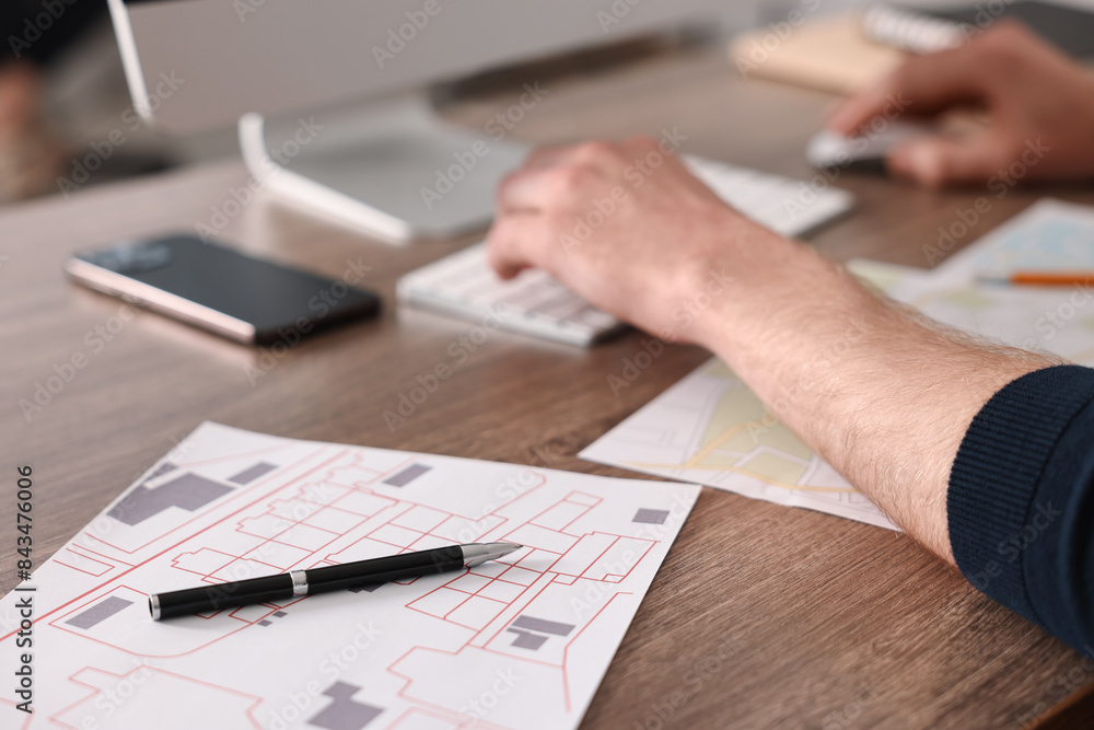 Cartographer working with cadastral maps at wooden table in office, closeup Cartographer working with cadastral maps at wooden table in office, closeup