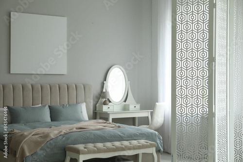 Folding screen, mirror and comfortable bed in bedroom. Interior design photo