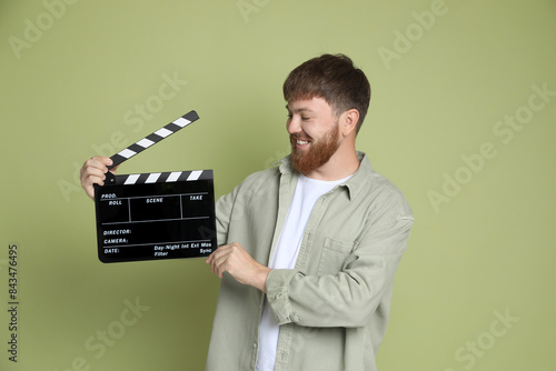 Making movie. Smiling man with clapperboard on green background