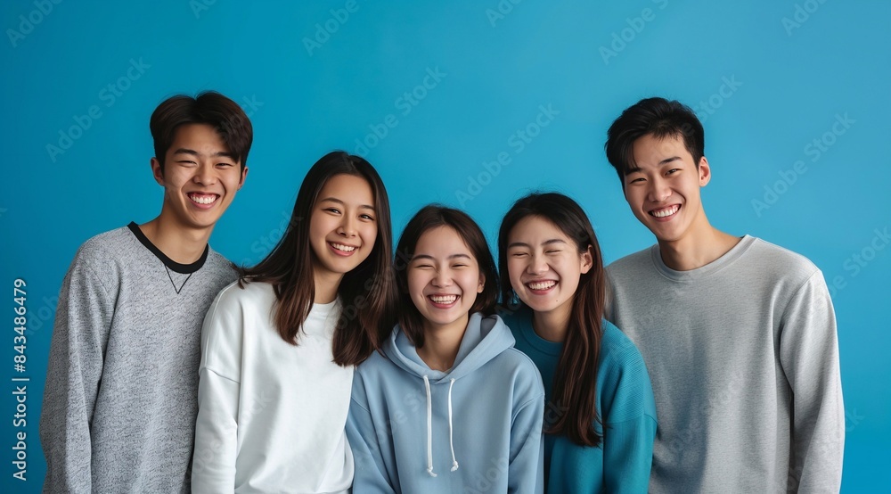 A portrait of korean young people early twenties. standing close together against an isolated blue background. They wear casual t-shirts or hoodies, exuding youthful happy energy. generative AI A portrait of korean young people early twenties. standing close together against an isolated blue background. They wear casual t-shirts or hoodies, exuding youthful happy energy. generative AI