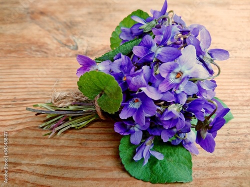 Violets flowers bouquet on wooden table. Wild common violet flowers (wood, sweet, English or garden violet) Viola odorata. Edible blossoms, used as salad decoration or candying. Violet flowers bouquet