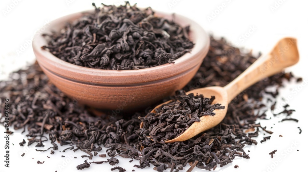 A bowl of black tea leaves and a spoon on top of them A bowl of black tea leaves and a spoon on top of them