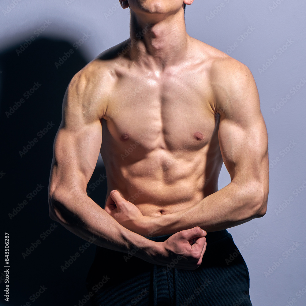 A topless male, fit, muscled. and athletic teenager fitness model lifting weights in a gym. A topless male, fit, muscled. and athletic teenager fitness model lifting weights in a gym.