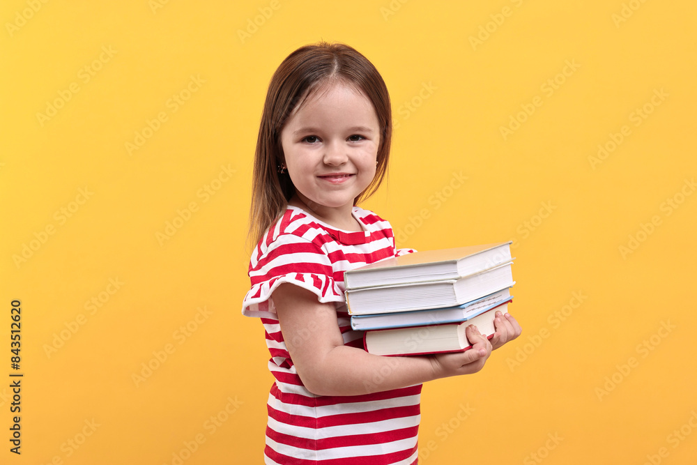 Cute little girl with books against orange background Cute little girl with books against orange background