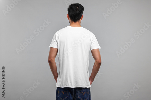 Man in white t-shirt on grey background, back view